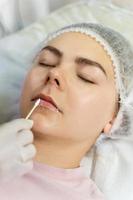 maquillador profesional permanente aplicando crema anestésica foto
