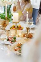 mesa festiva con comida, vino, flores y velas. foto