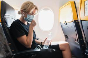 Woman wearing prevention mask during a flight inside an airplane photo