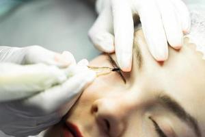 Young woman during professional permanent makeup treatment photo