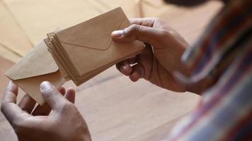 Man looks through stack of natural brown mailing envelopes video