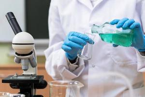 Scientist pouring substance from one flask to another in a laboratory photo