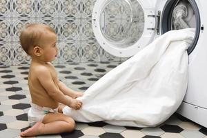 Cute baby boy beside the washing machine photo