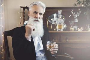 apuesto anciano barbudo con un vaso de whisky foto