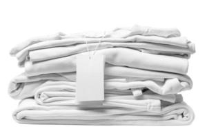 Stack of white clothes with a blank garment tag on white background photo