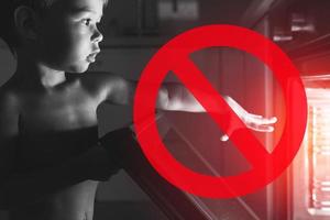 Baby and NO symbol near the oven. Concept of safety and possible problems with unattended children. photo