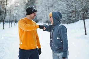 Two joggers greeting each other with a fist bump gesture during winter workout photo