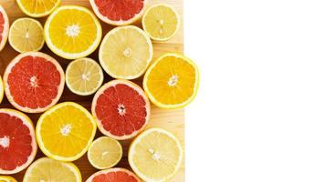 rodajas de cítricos como pomelo, naranja, limón y lima en una tabla de cortar con fondo blanco foto