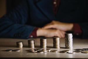 business woman hand calculating her money in the end of month with coin, calculator and calendar on wooden table photo