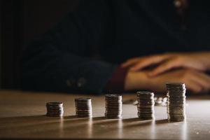 business woman hand calculating her money in the end of month with coin, calculator and calendar on wooden table photo