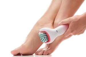 Female feet and electric foot scrubber or massage device on white background photo