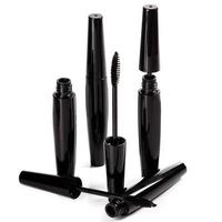 Black mascara brushes and containers on white background photo