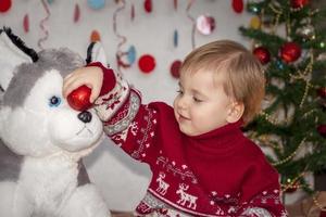 Portrait of a cute boy near a Christmas tree with a toy dog. Children's emotions. Christmas and new year. photo