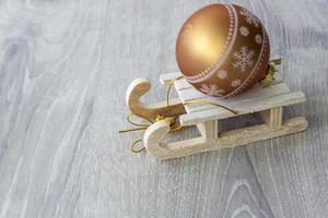 trineo de madera con una bola dorada de navidad. preparándose para el nuevo año. foto