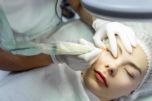 Young woman during professional permanent makeup treatment photo