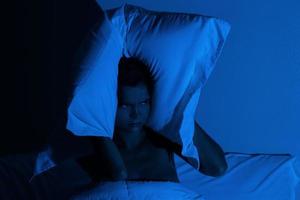 mujer en el dormitorio con una almohada en la cabeza foto
