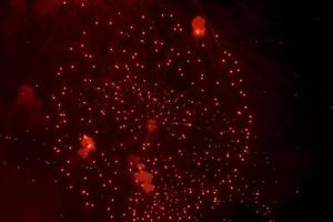 saludo. salpicaduras rojas y brillantes de fuegos artificiales en el cielo oscuro. foto