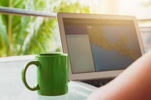 Green coffee mug and computer with a map on display. photo