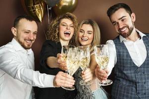 fiesteros bien vestidos celebrando vacaciones o eventos y bebiendo vino espumoso foto