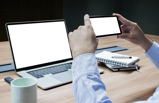 Businessman using smart phone to take picture of laptop screen and white screen background mock up on display laptop and smart phone with clipping path photo