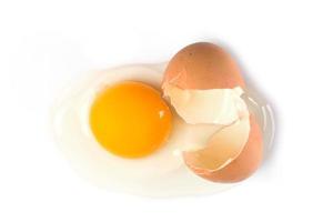 Broken chicken egg with a yolk and egg white pouring out photo