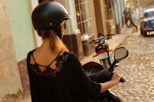 Woman driving scooter by the old city streets photo