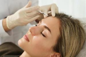 mujer durante inyecciones de relleno facial en clínica médica estética foto