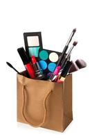 Different makeup objects in shopping bag on white photo