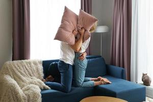 pareja feliz durante la pelea de almohadas en su apartamento foto