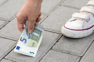 Woman is picking five euro banknote from the ground photo