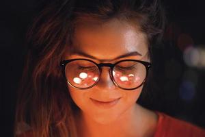 Young woman with reflection of glowing light balls in her eye glasses photo