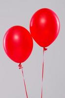 Two red balloons isolated on gray background photo