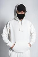 Man wearing white hoodie, black baseball cap and cloth face mask photo