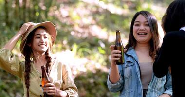 Group beautiful Asian women friends travelers relaxing at front of camping tent, They are standing to dancing and drinking beer and talking with fun and happy together video