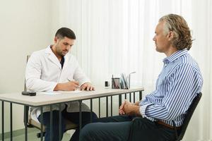 médico y paciente varón de mediana edad durante la consulta foto