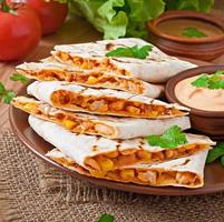 Mexican Quesadilla sliced with vegetables and sauces on the table photo