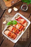 Delicious chicken rolls stuffed with green beans and carrots wrapped in strips of bacon photo