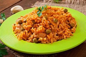 Pilaf with chicken, carrot and green peas on white plate photo