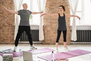 personas mayores activas durante el entrenamiento físico con una clase en línea en casa. foto