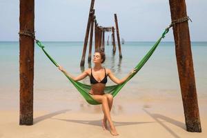 Woman is relaxing in the hammock hanging on old beams from the broken pier photo