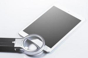 Closeup of magnifying glass and tablet computer photo