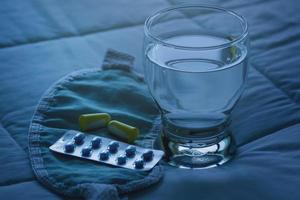 Blister pack of sleeping pills, blindfold and glass of water photo