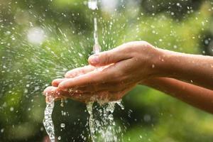 Wet female hands and clear water splashes photo