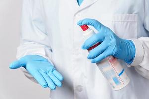 Doctor makes an additional disinfection of the gloves with a alcohol spray photo