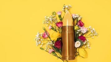 Pacifism and non-violence movement. Bullet and bunch of different flowers against yellow background. photo