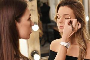 Pofessional make-up artist and her working process during makeup routine for young and beautiful model photo