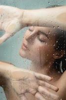 Portrait of sensual woman captured through wet glass photo