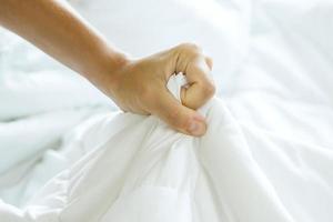 Female strong hand squeezing white bed sheet photo