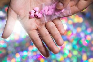 Man pouring heart shaped pills on palm from ziplock bag. photo