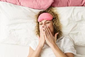 Beautiful woman with curly hair waking up after good sleep photo